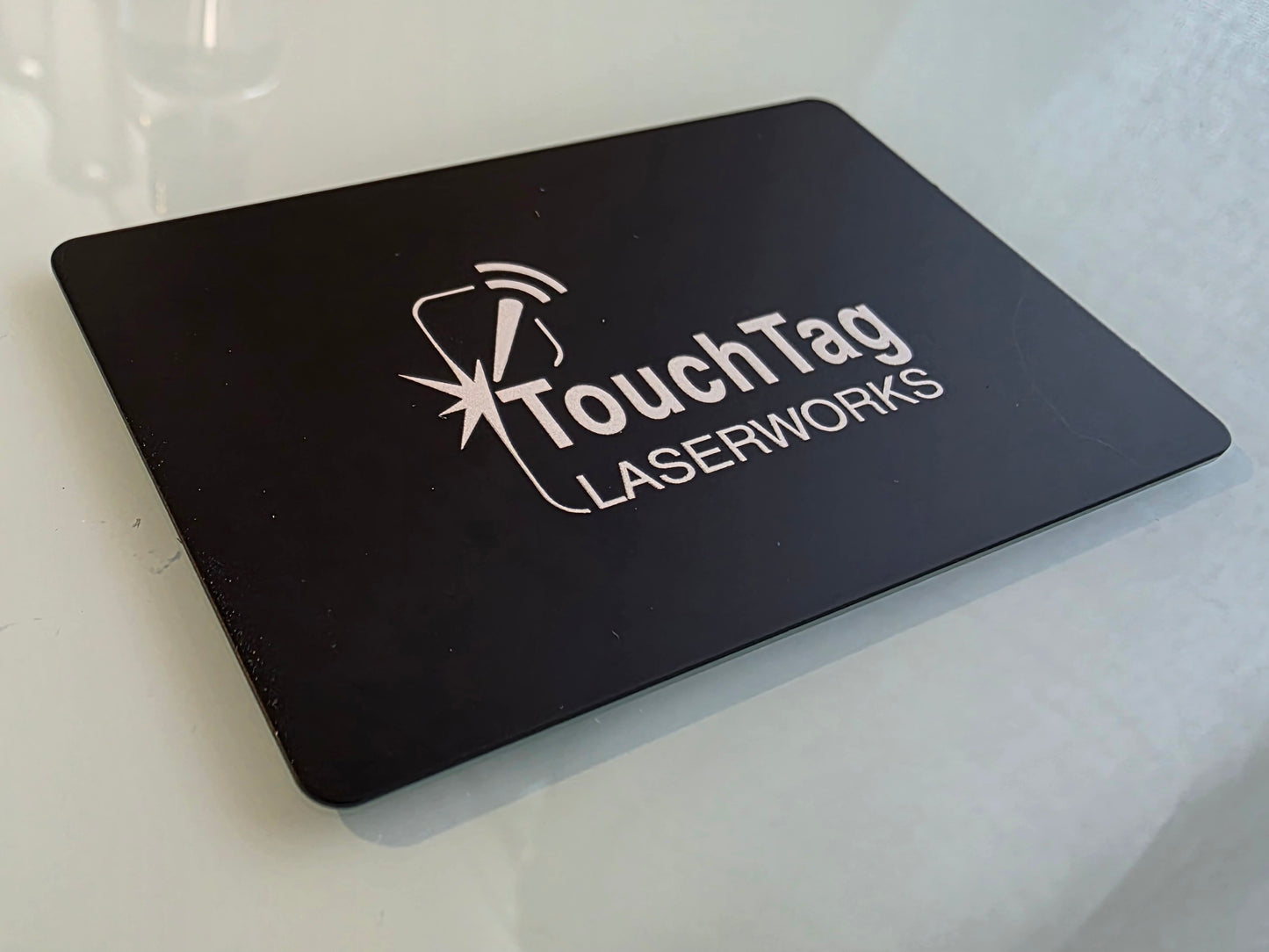 Black card with 'TouchTag Laserworks' logo on a white surface